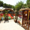 Area giochi all'aperto con scivolo, recinzione colorata e decorazioni vivaci.