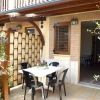 Terrazza esterna con tavolo e sedie nere, circondata da piante.