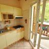 Cucina compatta con mobili gialli e porta aperta verso il balcone.