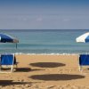Spiaggia con sedie a sdraio e ombrelloni blu.