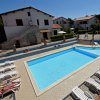 Piscina con lettini e villette in sfondo.