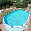 Piscina ovale con lettini bianchi intorno.