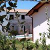 Ramo di ulivo in primo piano davanti ad edifici con mura in pietra e tetti in tegole.