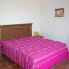 Camera con letto matrimoniale coperto da un copriletto rosa e mobili in legno.