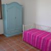 Camera con armadio azzurro, letto singolo con copriletto rosa e una piccola scrivania.