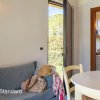Stanza con divano, tavolo tondo, cucina a vista e porta aperta sul verde.