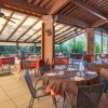 Ristorante all'aperto con soffitto in legno, tavoli apparecchiati e vista sulla vegetazione.