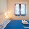 Camera con letto matrimoniale, copriletto blu, asciugamani piegati e finestra con tende.