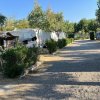 Area camping con roulotte e alberi lungo un vialetto di ghiaia.