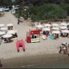 Spiaggia con ombrelloni e lettini, bagnanti e una torre di salvataggio.