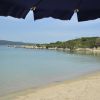Spiaggia sabbiosa con mare calmo e ombrellone blu.