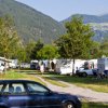 Auto e roulotte in un campeggio montano soleggiato.
