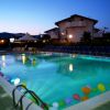 Piscina di sera con palloncini colorati galleggianti, circondata da lettini.