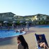 Piscina con molte persone e lettini. Edifici residenziali sullo sfondo.