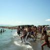Persone corrono verso il mare su una spiaggia affollata.
