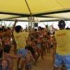 Animatori in giallo ballano con bambini sotto un gazebo.
