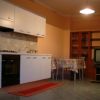 Una cucina con mobili bianchi, tavolo con tovaglia colorata e un televisore.