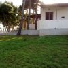 Una casa con veranda vista dal giardino erboso con alberi intorno.