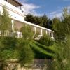 Una villa immersa nel verde con balconi e un tetto spiovente, vista dal giardino.