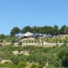 Una collina alberata con una struttura bianca in cima, circondata da vegetazione.