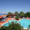 Piscina all'aperto con lettini, ombrelloni e vista mare.