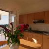Cucina con mobili in legno, tavolo con fiori in primo piano e vista su terrazza soleggiata.