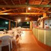 Un bar all'aperto con sedie bianche e un bancone. Il soffitto è in legno e ci sono luci soffuse.