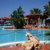 Piscina con sdraio, ombrelloni e un grande masso decorativo di fronte.