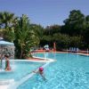 Una piscina con una fontana a ombrello, palme e piante; due persone in acqua.