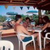 Persone sedute a un tavolo sotto un gazebo con ombrelloni in piscina.