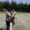 Due persone su campo da tennis, una con racchetta.