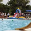 Piscina con giochi gonfiabili e persone intorno.