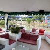 Area lounge all'aperto con divani bianchi e cuscini rossi.