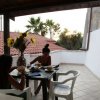 Persone a tavola su terrazza con tetti in tegole rosse.