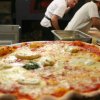 Pizza margherita con cuochi sullo sfondo.