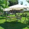 Tavoli all'aperto con ombrelloni bianchi su prato verde.