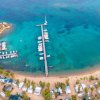 Veduta aerea di un molo con barche e campeggio sulla spiaggia.