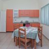 Cucina moderna con tavolo apparecchiato e mobili arancioni.