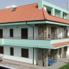 Edificio a due piani con tetto rosso e balconi.