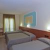 Camera d'albergo con tre letti singoli e luci soffuse.