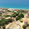 Veduta aerea di un'area costiera con rovine storiche e il mare sullo sfondo.