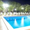 Piscina illuminata di notte con lettini e alberi.