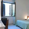 Stanza con letto singolo, scrivania con computer, valigia e finestra aperta.