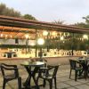 Terrazza coperta con tavoli e sedie in plastica, decorata con festoni, immersa nel verde.