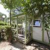 Una piccola veranda di legno verde circondata da alberi.