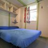 Una piccola stanza con un letto matrimoniale e scaffali, decorata con toni verdi e blu.