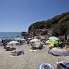 Spiaggia con ombrelloni colorati, persone che prendono il sole e mare sullo sfondo.