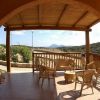Una veranda coperta con mobili di vimini e vista su colline verdi.