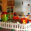 Un'area giochi per bambini con casetta, recinzione e giochi colorati.