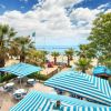 Spiaggia con palme e ombrelloni a strisce blu e bianche.